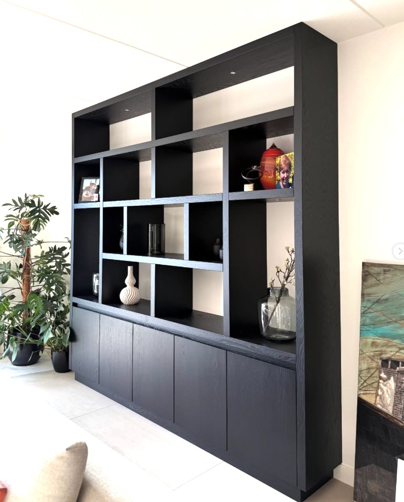Maatwerk boekenkast in zwart eiken die als roomdivider de ruimte verdeelt